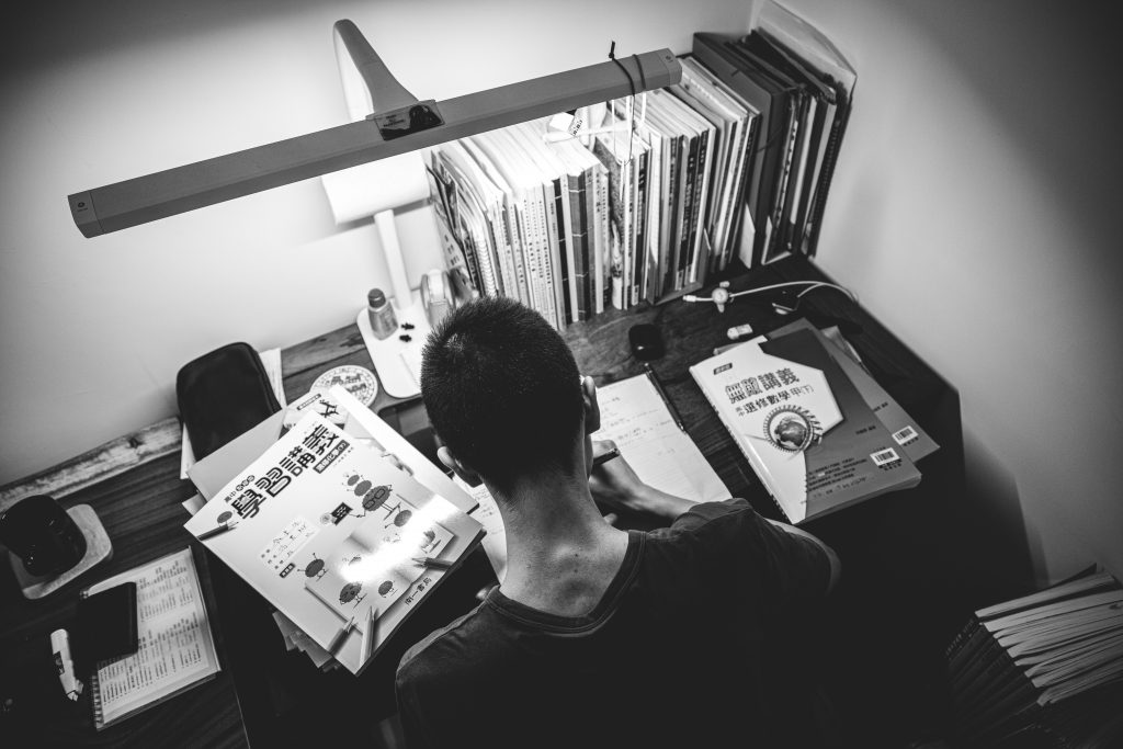 man in black crew neck shirt standing in front of books
