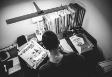man in black crew neck shirt standing in front of books