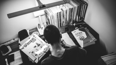 man in black crew neck shirt standing in front of books