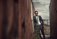 man in black suit standing on brown wooden bridge during daytime