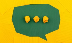 three crumpled yellow papers on green surface surrounded by yellow lined papers