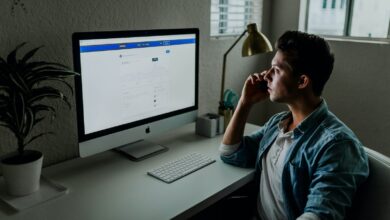 man in blue denim jacket facing turned on monitor