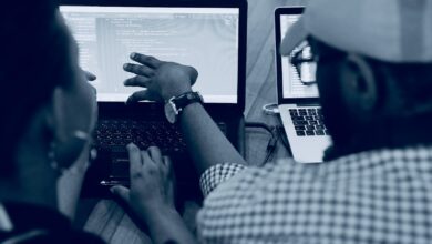 woman using laptop computer beside person wearing hat