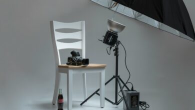 black video camera on white wooden chairs beside photo shooting umbrella