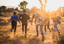 fiver person running on the field near trees