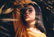 woman holding her head white standing in the middle of plants