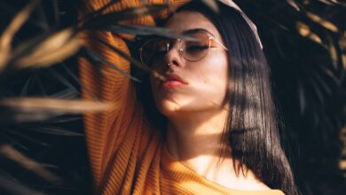 woman holding her head white standing in the middle of plants