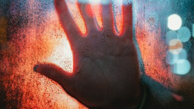 A dramatic depiction of a hand pressed against a foggy, illuminated window.