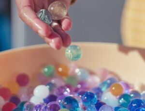 person holding pink yellow and silver beads