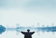man in black jacket standing near body of water during daytime
